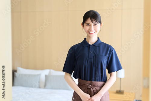 客室で笑顔で立つホテルの女性清掃員