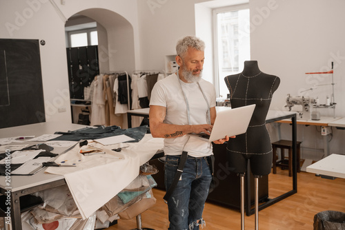 Foto A designer works on a laptop in a bright studio surrounded by materials and tools for creation