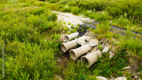 Quadro su tela Aerial view of concrete drainage culvert pipes under a dirt road crossing surrou