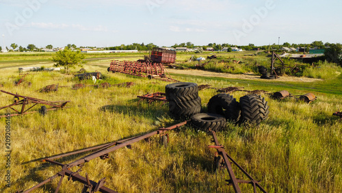 Cuadro en lienzo Old rusty agricultural trailers and scrapped farm machinery parts sitting in a grassy field yard