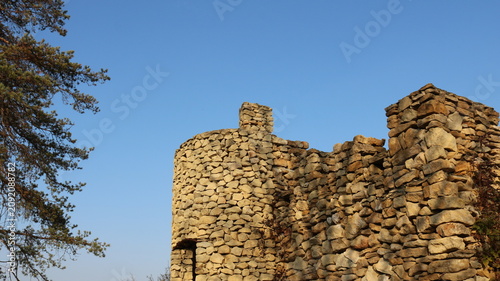 Canvastavla A dilapidated round tower and an adjacent wall, built of light-colored wild stone
