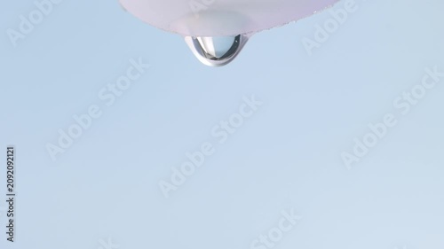 A transparent drop of serum slowly flows down, macro, blue background.