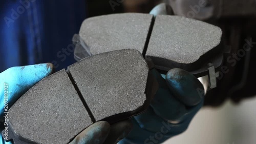 Close-up of two new brake pads for a car in the hands of a car mechanic in a workshop.