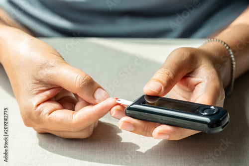 Bild auf Leinwand Woman's hands checking diabetes and hyperglycemia with digital blood sugar meter