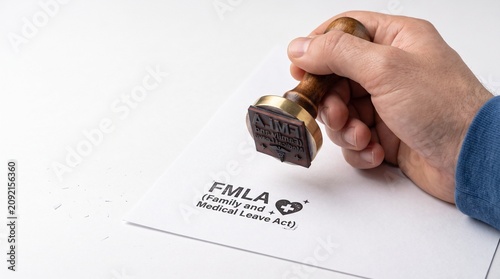FMLA Family and Medical Leave Act rubber stamp on paper, hand stamping official document for employee benefits, legal labor rights concept