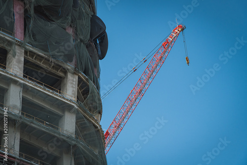 Картината върху платно Red luffing jib crane works behind reinforced concrete structure wrapping with g