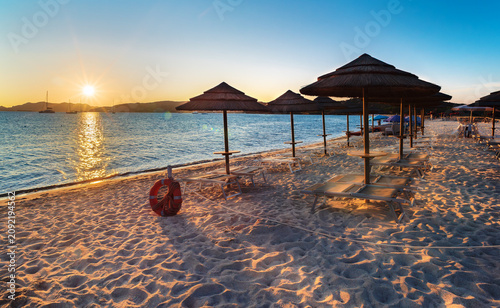 Summer sunrise over the sandy beach of Tavolara with parasols and sun loungers, Loiri Porto San Paolo, Sardinia, Italy