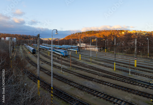 Fotografía Railway marshalling yard in Michle, Prague, with passenger trains and multiple railway tracks under dramatic winter light and clear evening sky