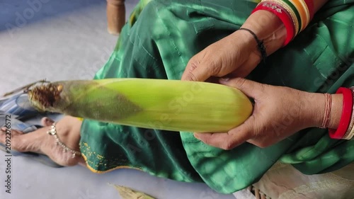 An Indian woman peeling corn cobs