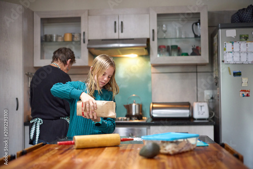 Young girl baking with her grandmother in a cozy home kitchen learning to cook together
