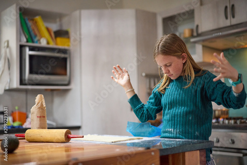Young girl baking with her grandmother in a cozy kitchen, rolling dough and learning to cook