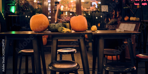 Bilde på lerret Pumpkins and decorative gourds arranged on outdoor restaurant tables, creating a cozy autumn evening atmosphere for seasonal hospitality and fall decor themes