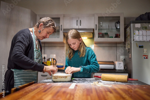 Young girl baking with her grandmother in a cozy home kitchen learning to make pastry