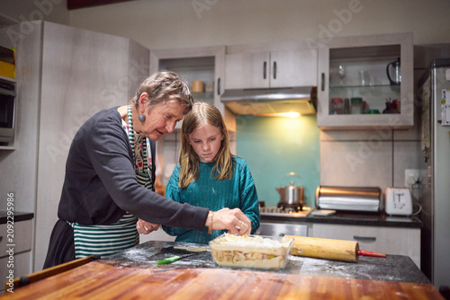 Grandmother teaching young girl to bake together in a cozy home kitchen