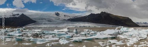 Panel kuchenny z motywem Floating icebergs drift across Fjallsárlón glacier lagoon beneath the mighty Vatnajökull glacier in southeast Iceland, creating a dramatic Arctic landscape of ice, mountains and glacial beauty.