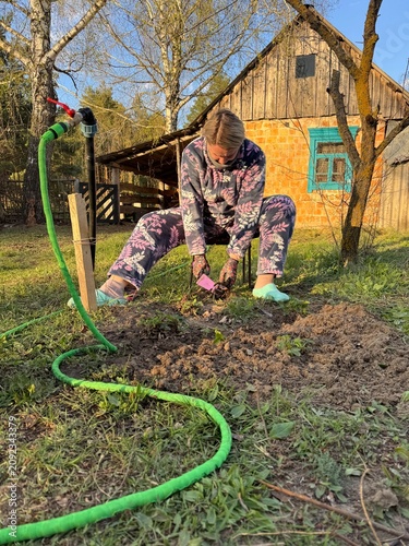 A woman weeds the garden bed. Removing weeds.