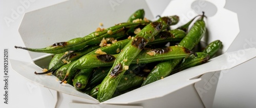 Freshly Grilled Shishito Peppers with Garlic and Seasoning in Takeout Container for Asian Cuisine and Food Photography