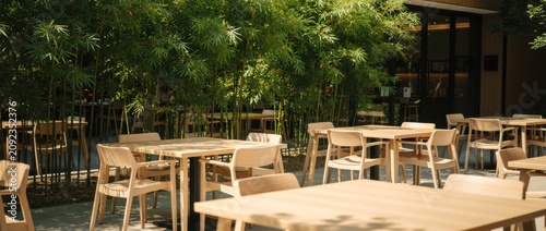 Peaceful outdoor cafe area with wooden furniture surrounded by lush green bamboo plants in a bright and inviting atmosphere for relaxation and dining.
