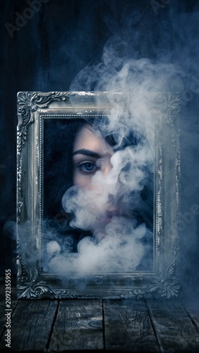 A person’s face partially obscured by smoke behind a decorative frame.