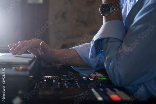 DJ controlling music system during live event with laptop and controller