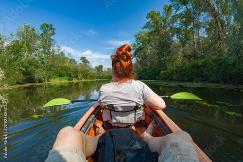 POV Couple Kayaking on a Calm Summer River Surrounded by Lush Green Trees