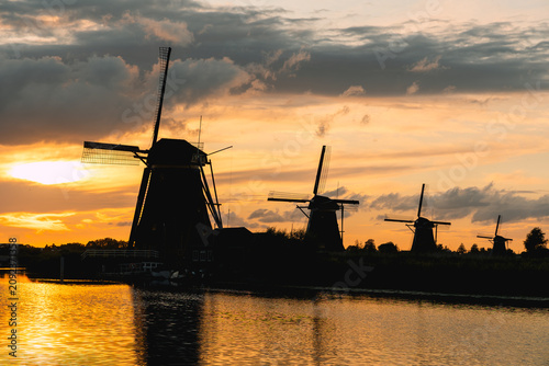 фотографія Kinderdijk windmills silhouetted at sunset, golden sky reflecting in canal water