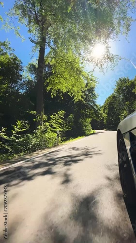 convertible car in sunny nature on a bright summer day. wide angle pursuit shot - vertical video for reels and story