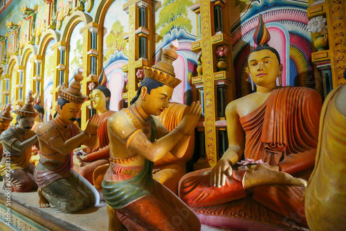 Принти на полотні Traditional colorful Buddha and bowing disciple statues inside Wewurukannala Vihara