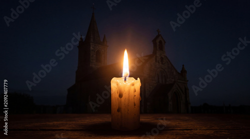 Glowing candle flame symbolizing peace and hope with church silhouette background
