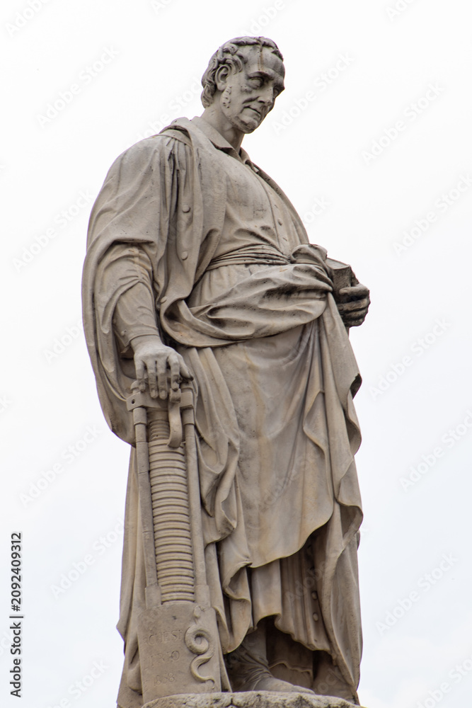 Fototapeta premium Statue of Alessandro Volta holding a Book and Voltaic Pile on a White Background. Como city Italy. Italian physics
