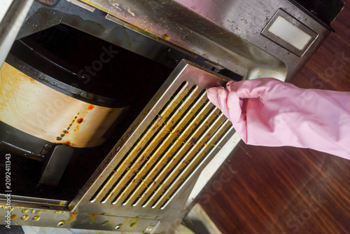 Housekeeping hands trying to removing a filters from cooker hood or chimney for cleaning. Replacing filter in modern kitchen hood or kitchen chimney maintenance for kitchen appliance.