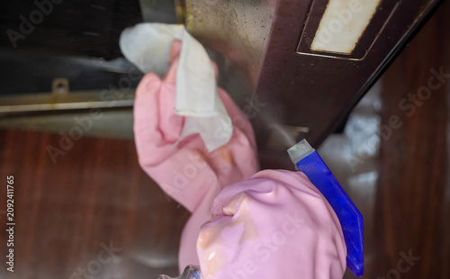 Hand in pink glove cleans kitchen hood or kitchen chimney filters. Cleaning kitchen extractor to remove grease by microfiber cloth.
