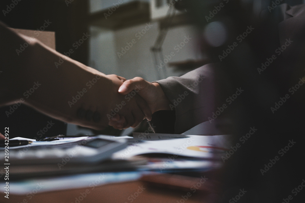 Fototapeta premium Business partners shaking hands over documents during meeting