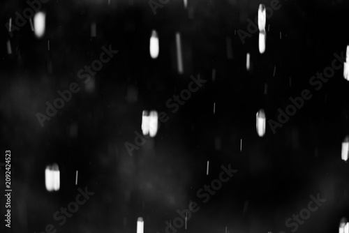 Abstract black and white background with falling rain drops or snow particles, motion blur effect, overlay texture for design