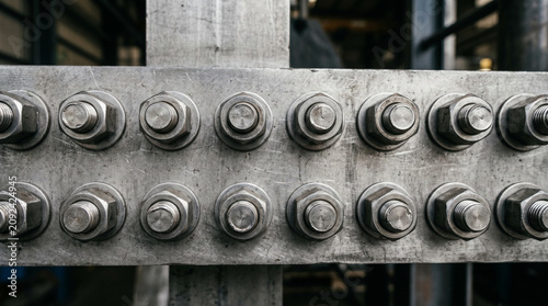 Close-up of heavy industrial bolts and nuts on a steel girder beam.