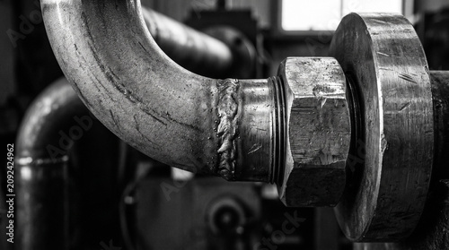 Close-up of industrial metal pipes and bolted joints.