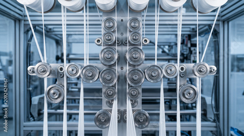 Close up of industrial loom rollers with white threads.