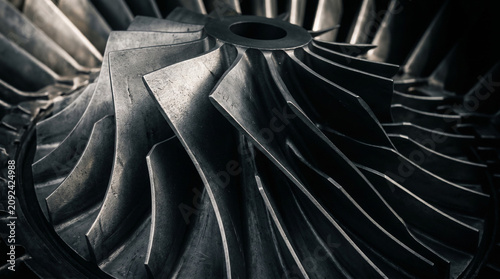 Close up of metallic industrial turbine blades with mechanical detail.