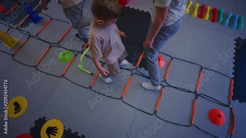 Young children participate in engaging fitness drills, utilizing an agility ladder and cones. Kids are actively playing and developing their physical skills in a structured environment.