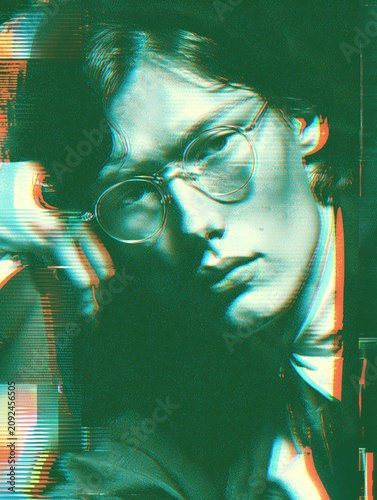 Close-up portrait of a young man wearing round glasses, shown with heavy color distortion and horizontal glitch bands on a dark background.