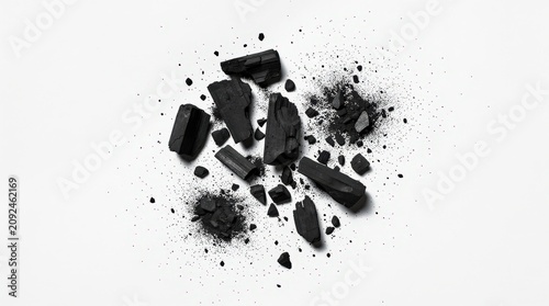 Black charcoal chunks and powder scattered on a white surface, displaying texture and contrast.