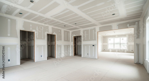 Interior of a new residential home under construction featuring installed drywall with taped and mudded seams.