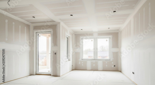 Interior of a new residential house under construction with installed drywall and plastered joints in a room.