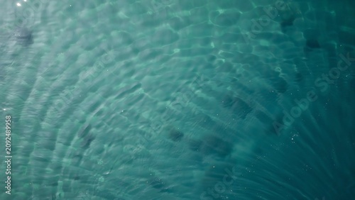 Closeup view of shimmering turquoise ocean water with gentle ripples and sunlight patterns reflecting on the surface