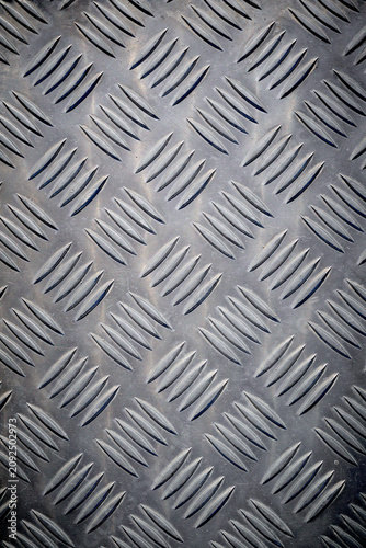 Background created with the foreground texture of a grooved metal surface on a pedestrian crossing to prevent slipping.