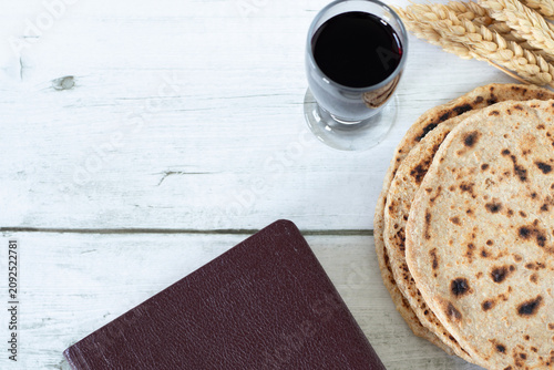 Obraz na plátne Passover bread, holy bible, glass of wine, and wheat on wooden table