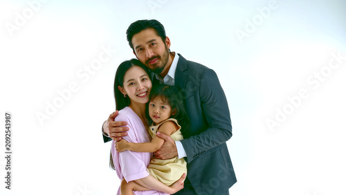 A joyful studio portrait of a loving Asian family of three embracing against an isolated white background. The father, mother, and young daughter share a happy, affectionate moment,