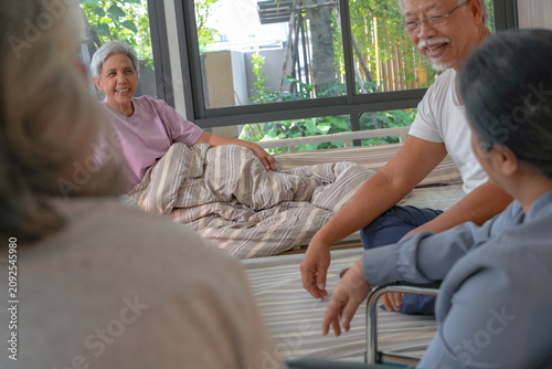 Photos Elderly Asian friends gather to chat and laugh together near care beds, one in a