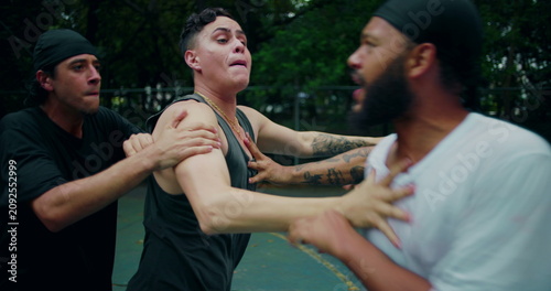 фотографія Hispanic and African descent men arguing on basketball court, friend intervenes