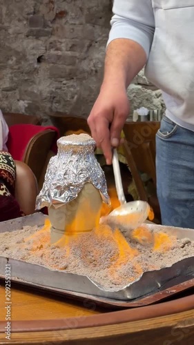 Traditional Turkish Testi Kebab is prepared and served in sealed clay pot surrounded by flames during restaurant presentation. Authentic Anatolian cuisine, live cooking, gastronomy, travel